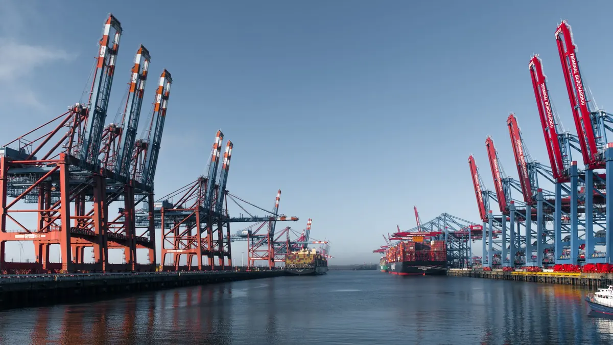 Containerterminal mit Kränen am Wasser.